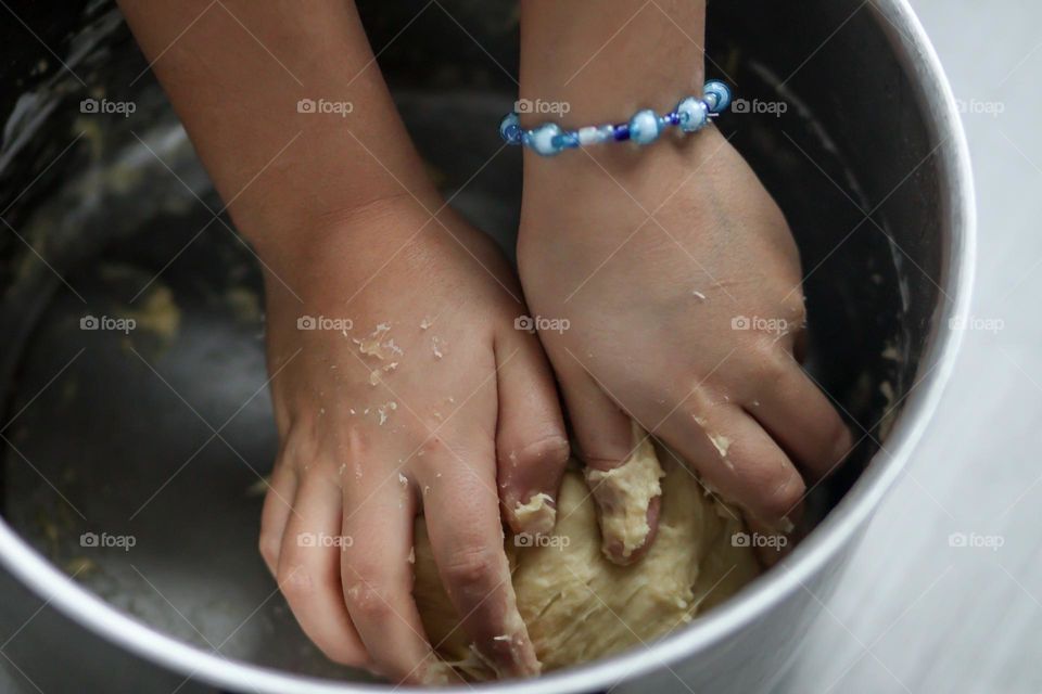 Child's hands are mixing bread dough