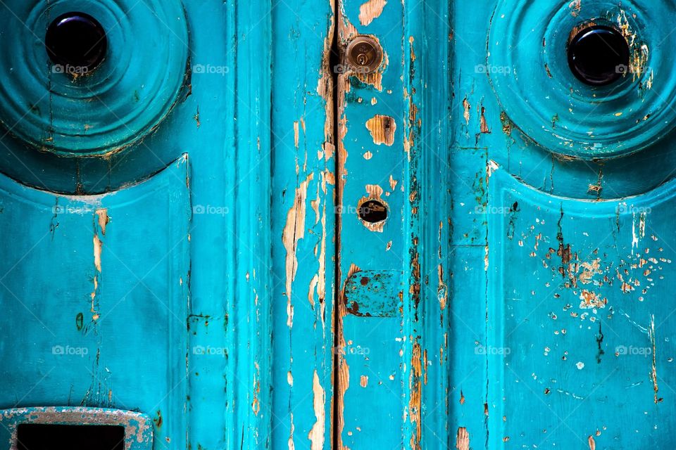 Turquoise doorway showing signs of weathering.