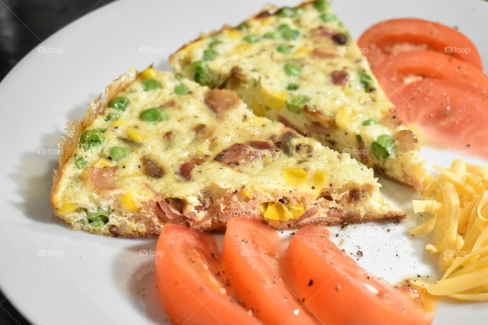 Homecooking cooking Frittata at home and adding and mixing ingredients and removing the Frittata from the pan for cutting and serving on a white plate with tomatoes. Healthy home cooking in kitchen. Breakfast and lunch food preparation. 