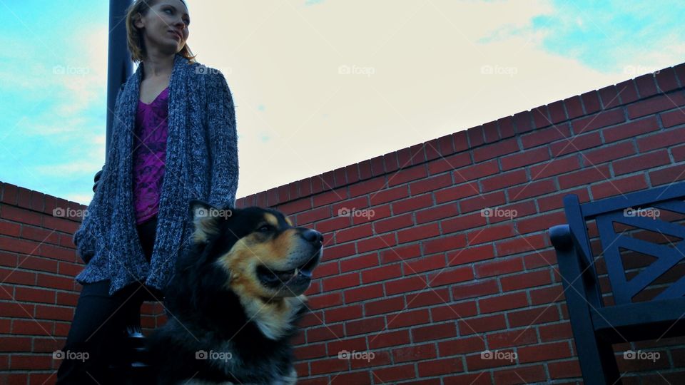 Woman with dog standing against the brick wall