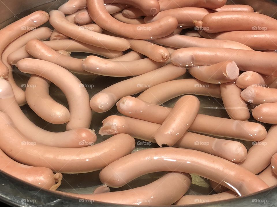 Many boiled industrial sausages in a pot 