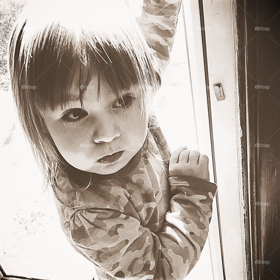 Close-up of small girl looking from window