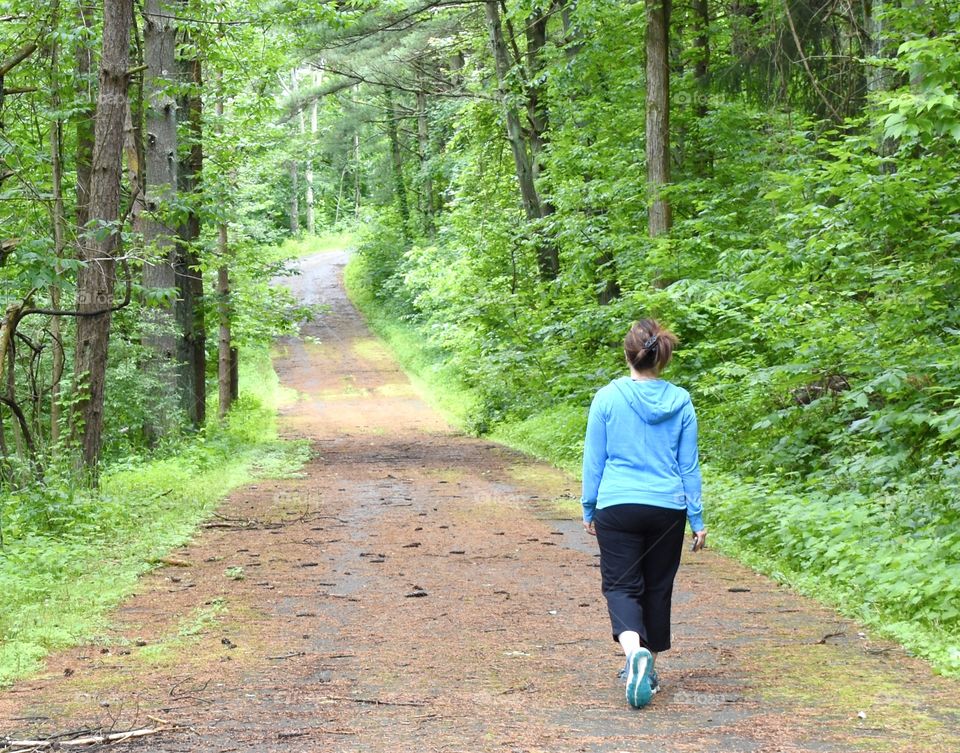 Woman going for a walk on a country road with trees on both sides