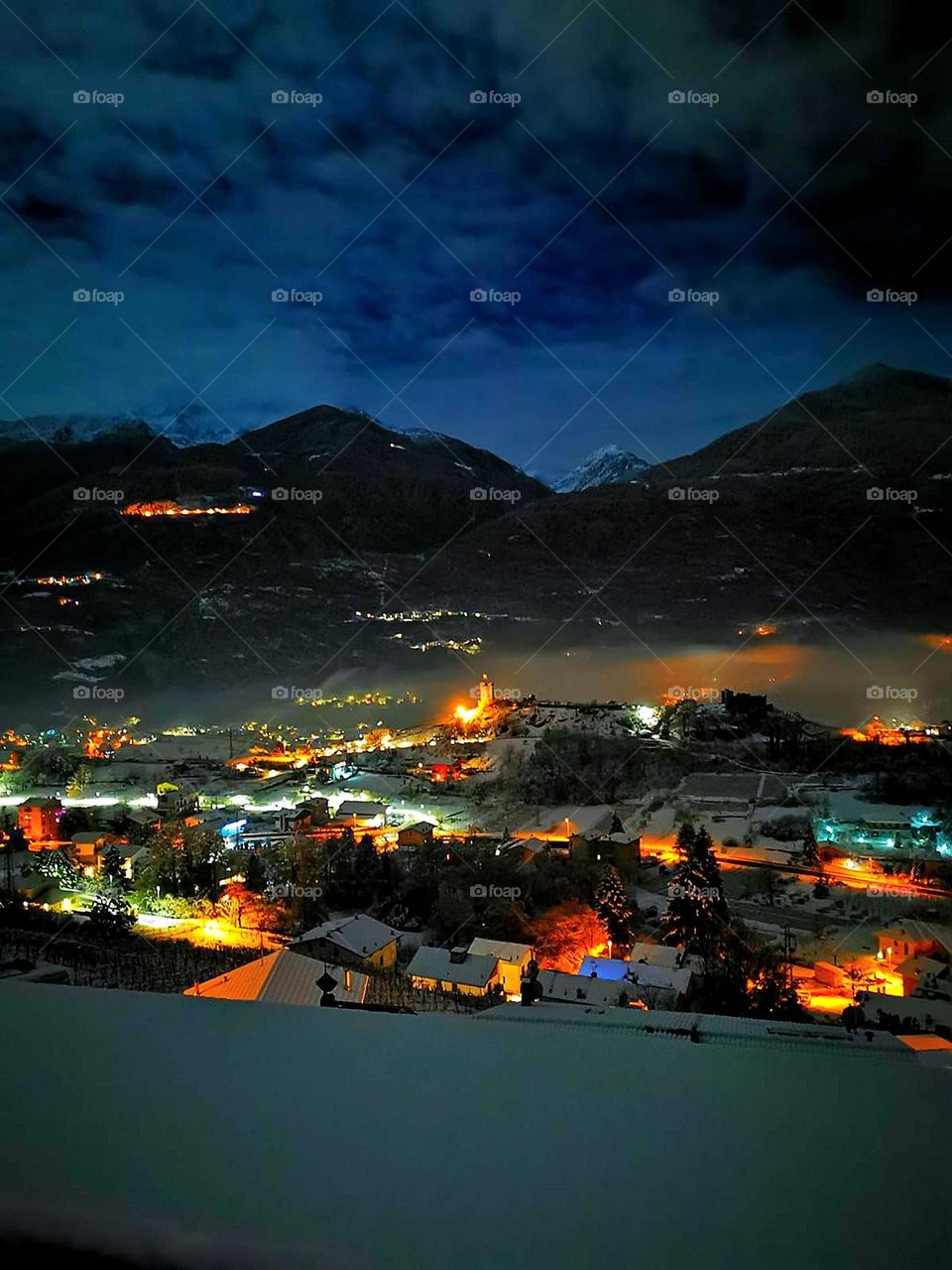 Winter fairy tale. Top view of a small town. Small city lights. The city is surrounded by mountains. Waiting for christmas