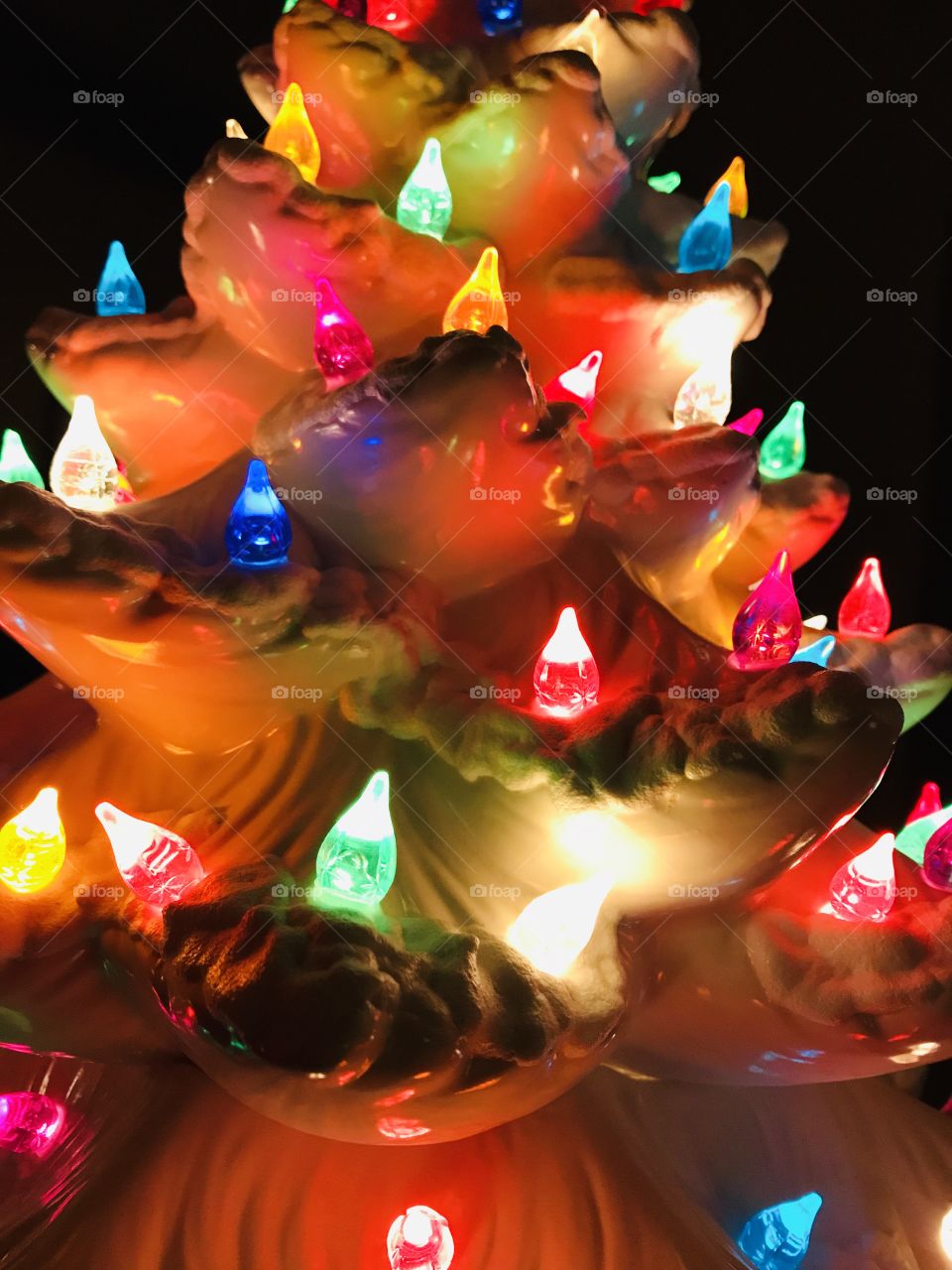 Antique white ceramic Christmas tree with colorful lights close up