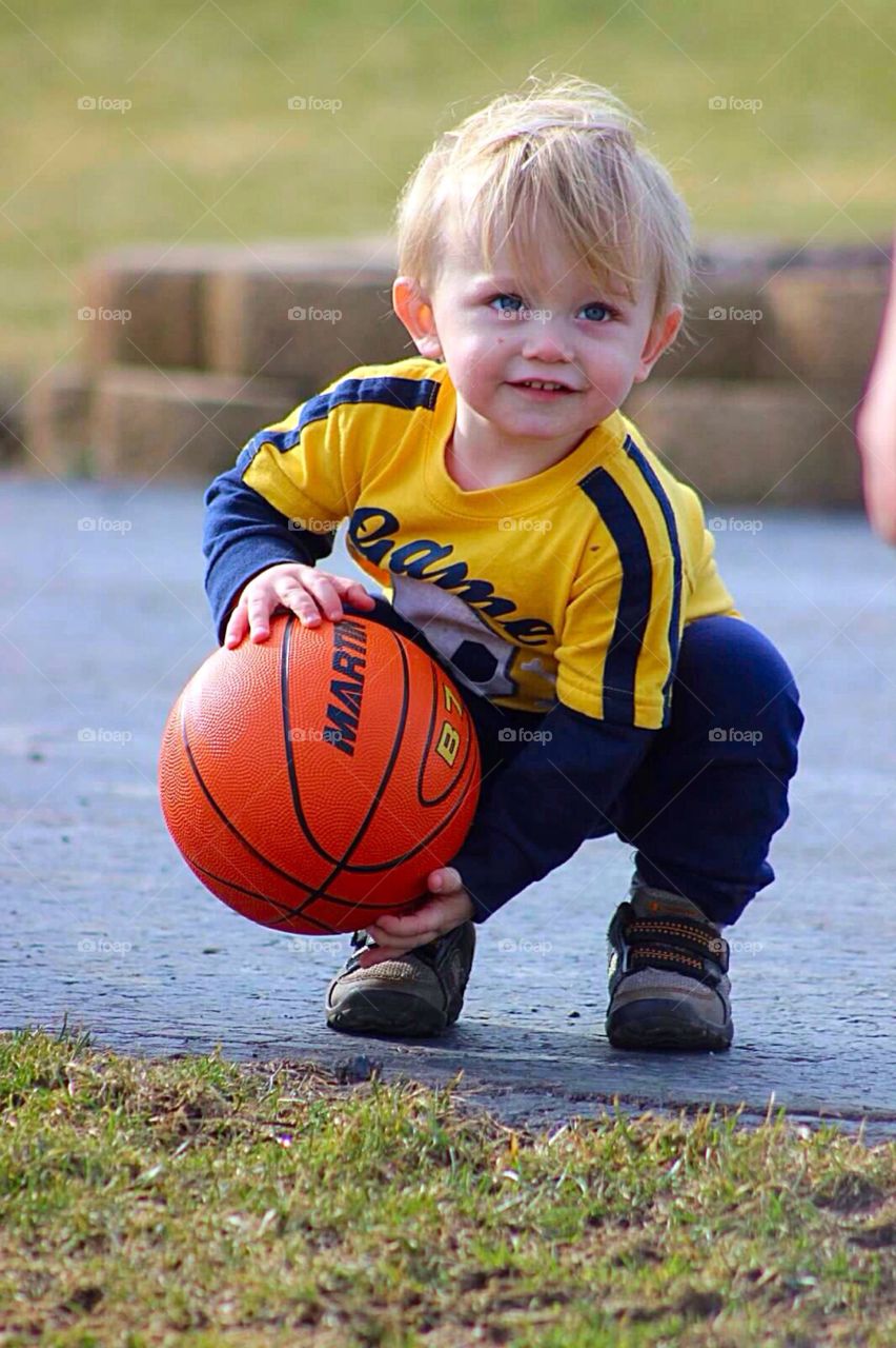 Game On. 18 month old little boy shooting hoops. 