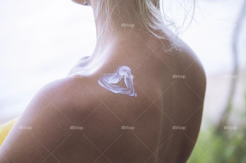 a young woman has a heart painted on her shoulder with cream