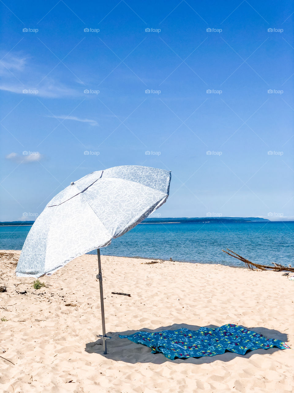 Beach umbrella with pretty shadow as sun blue hues in front of the ocean. 
