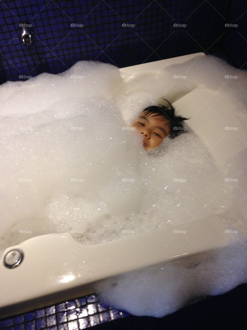 my grandson playing in the bathtub covering himself with soap suds