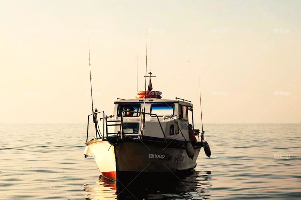 Close-up view of a fishing boat floating on the water with a clear sky in the background