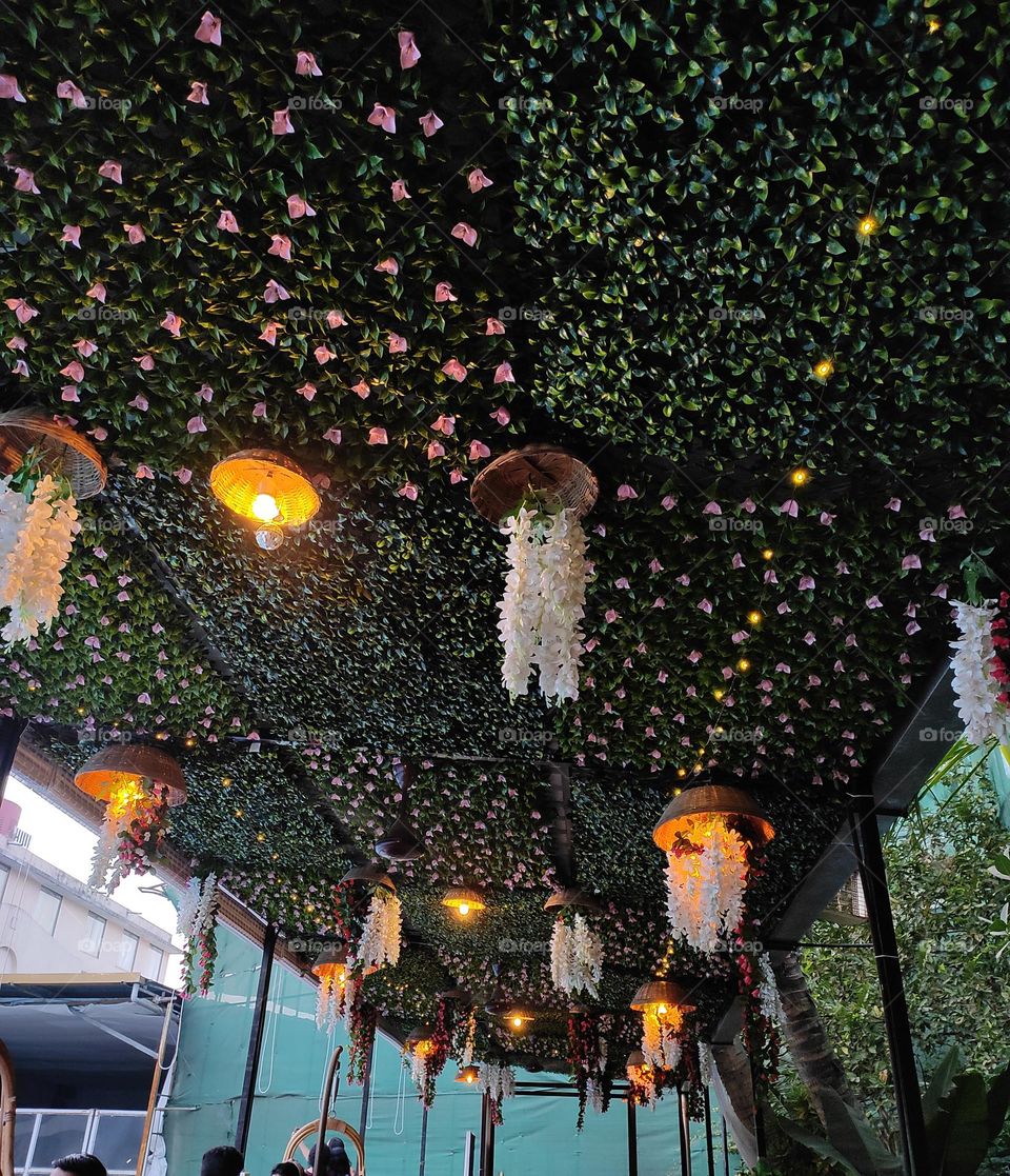the restaurant's ambiance with a stunning ceiling adorned with lifelike fake flowers and lush green grass. A captivating, nature-inspired setting to elevate your dining experience.