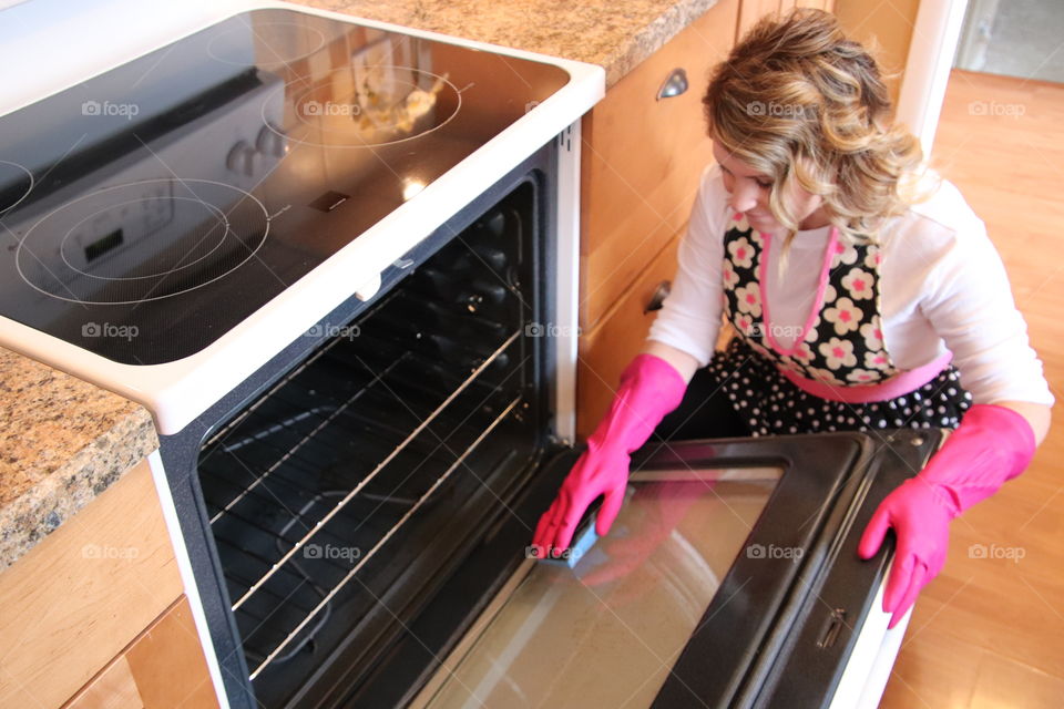 Woman cleaning oven wearing Playtex glove and using OCedar sponge 