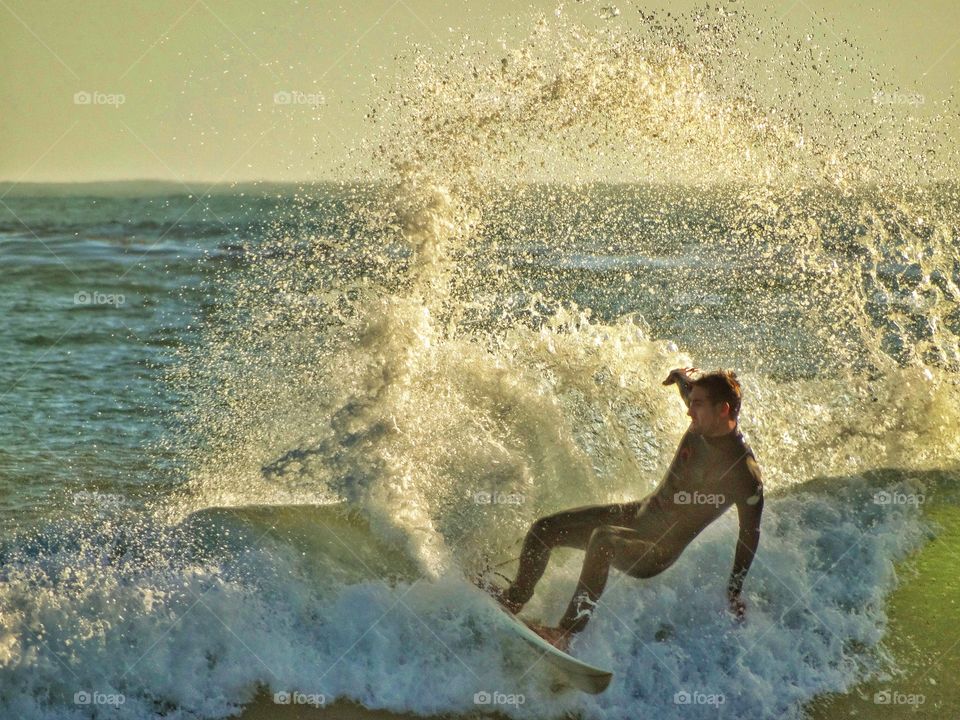 Surfing At Sunset. Pro Surfer On The Waves During The Golden Hour
