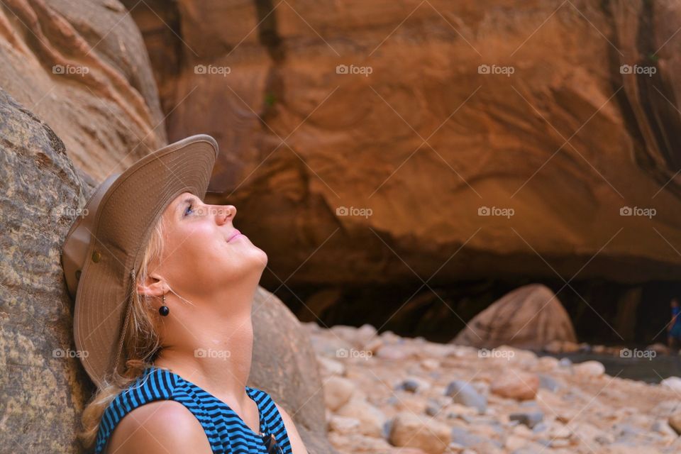 Smiling woman in hat sitting against rock