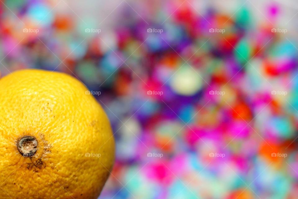 Close-up of a yellow lemon against a colorful background