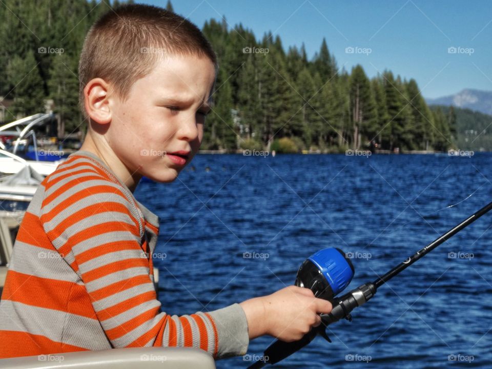 Little boy holding fishing rod on the lake