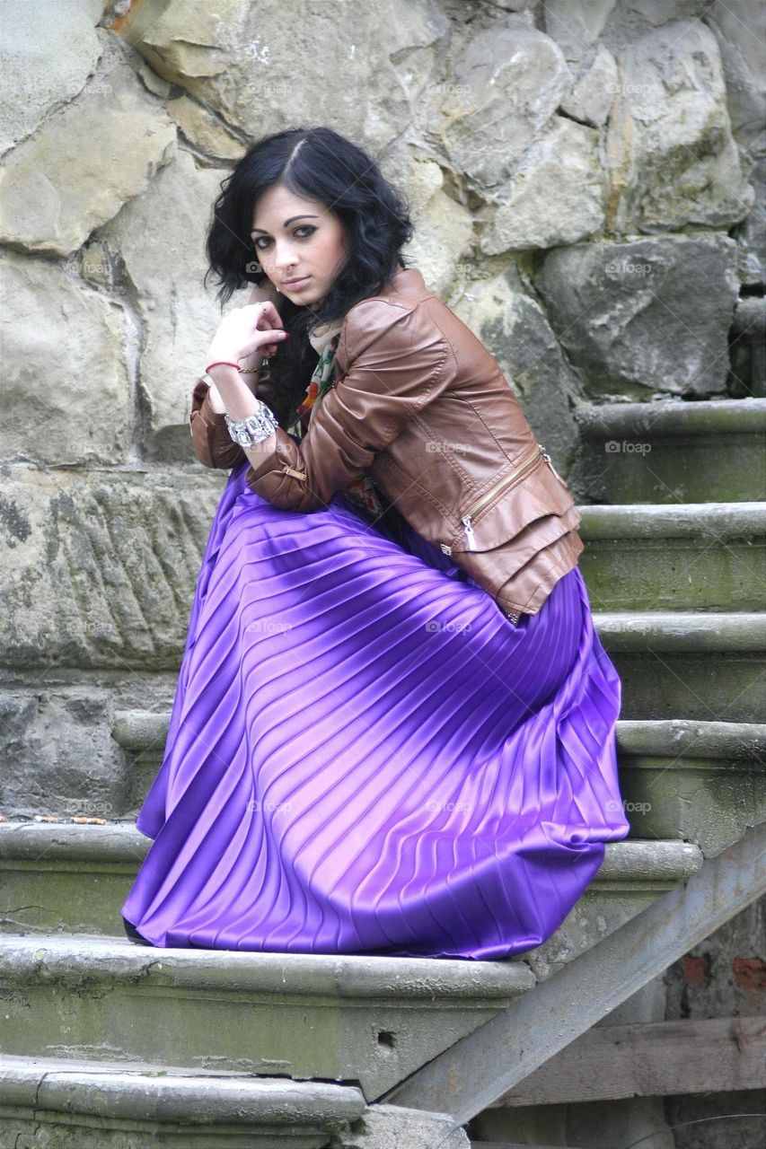 a beautiful girl in a chic skirt poses on the stairs