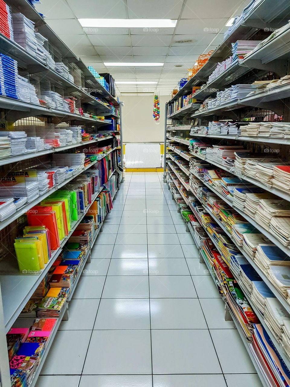 Bookcases and office stationery supplies, viewa in shops, office stationery displayed on shelves, two shelves facing each other, lighting right between them