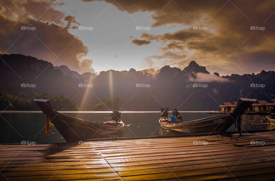 Morning in Thailand. Morning after sunrise raised up, sun rays hit the boats and wooden pier, Khao Sok national park, Thailand.