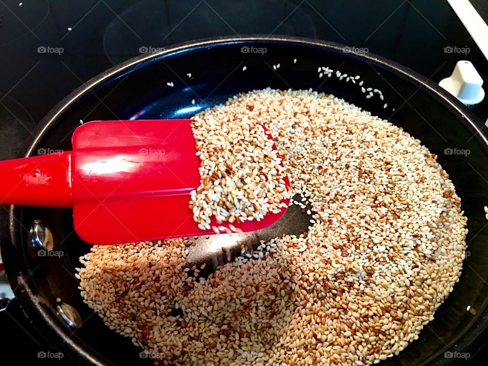 Bright red silicon spatula closeup stirring toasting sesame seeds