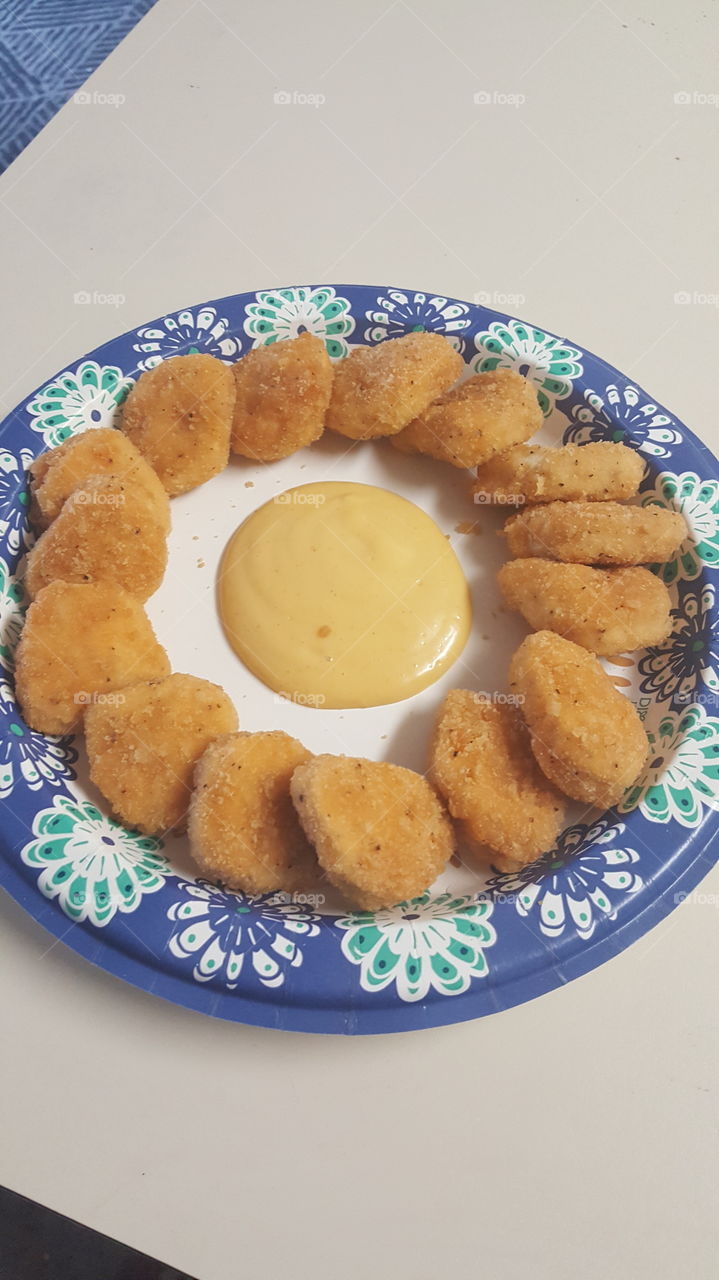 A display of a homemade chicken nugget lunch with a honey mustard center for dipping
