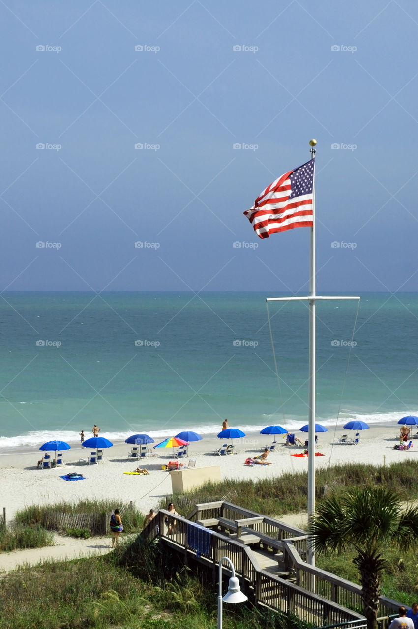 An American Flag blows in the wind at the beach. 