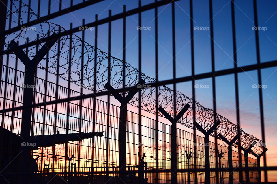 View through a barbed wire fence with beautiful colorful sunset sky in Dieppe France