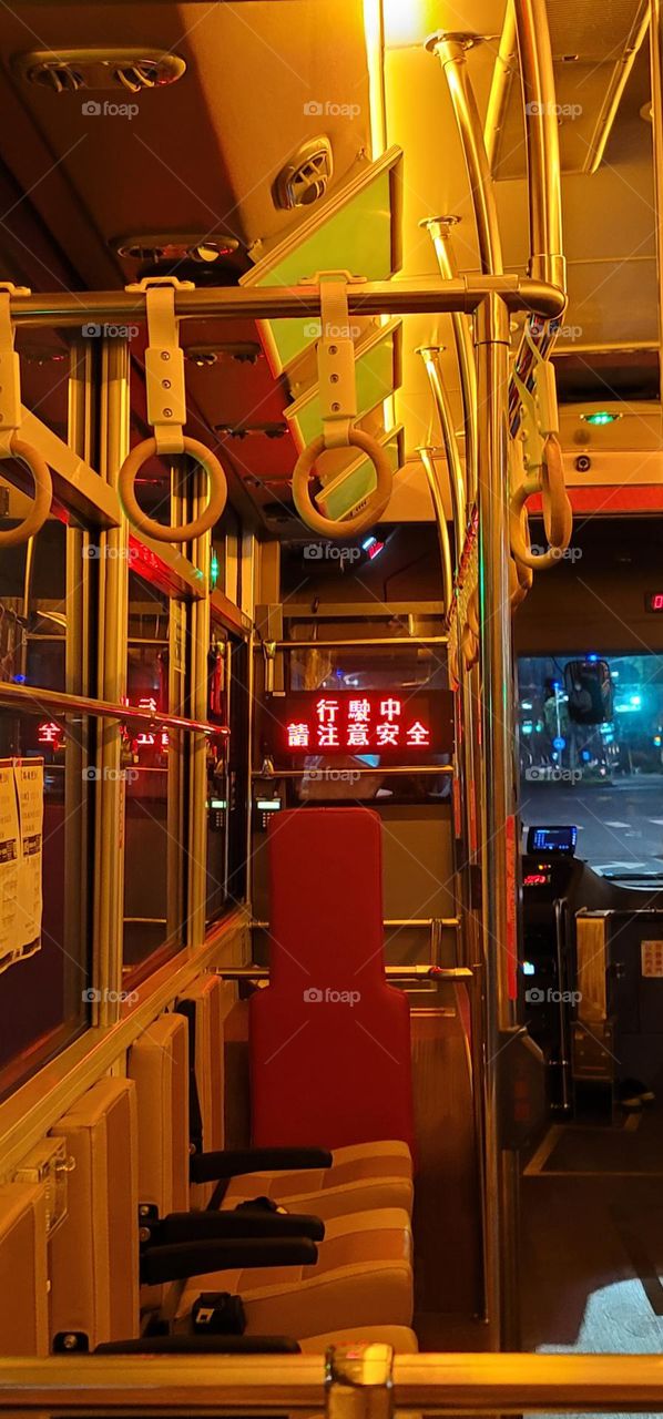 A retro-style bus with a warm yellow light interior. The marquee reads "Please pay attention to safety while driving" in Chinese