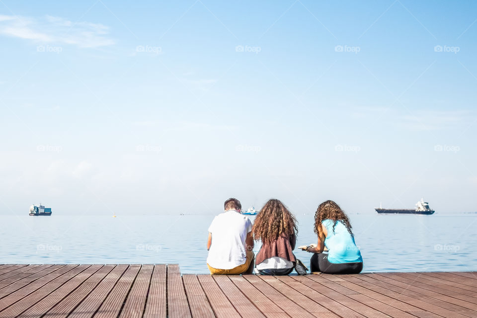 Friends Sitting On Wooden Dock