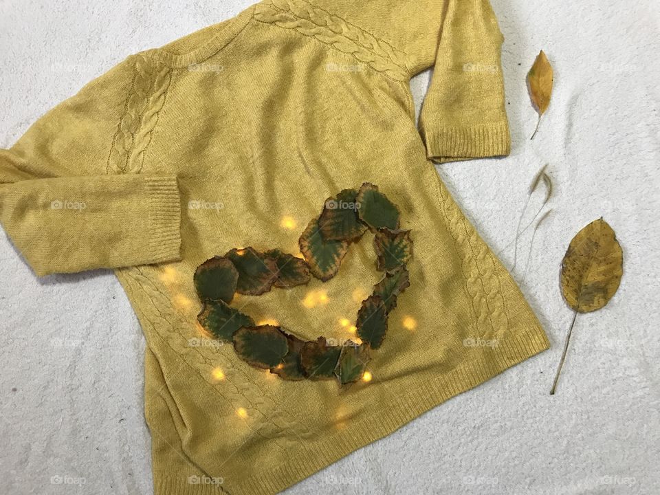 Yellow sweater with autumn leaves in the shape of a heart.