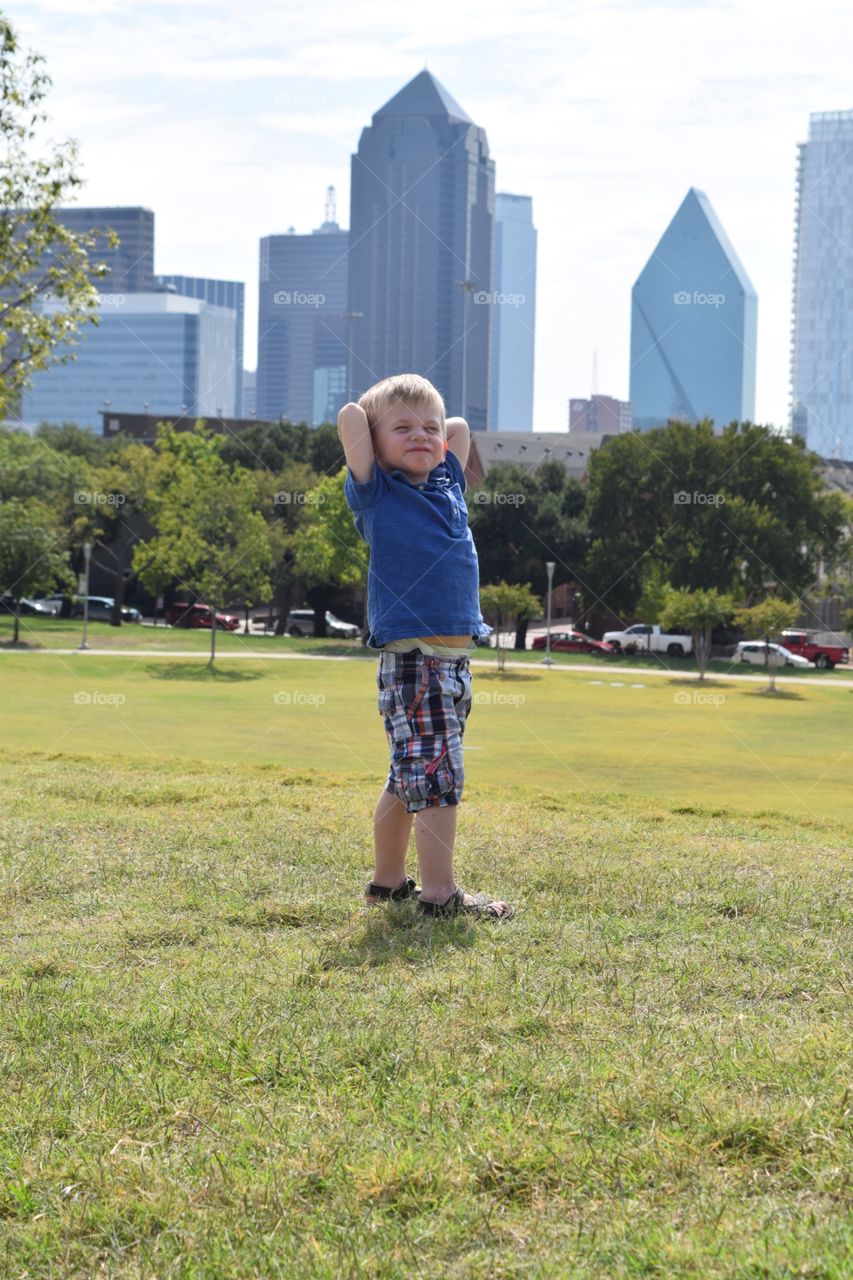 Boy being silly at park. Toddler posing silly at city park