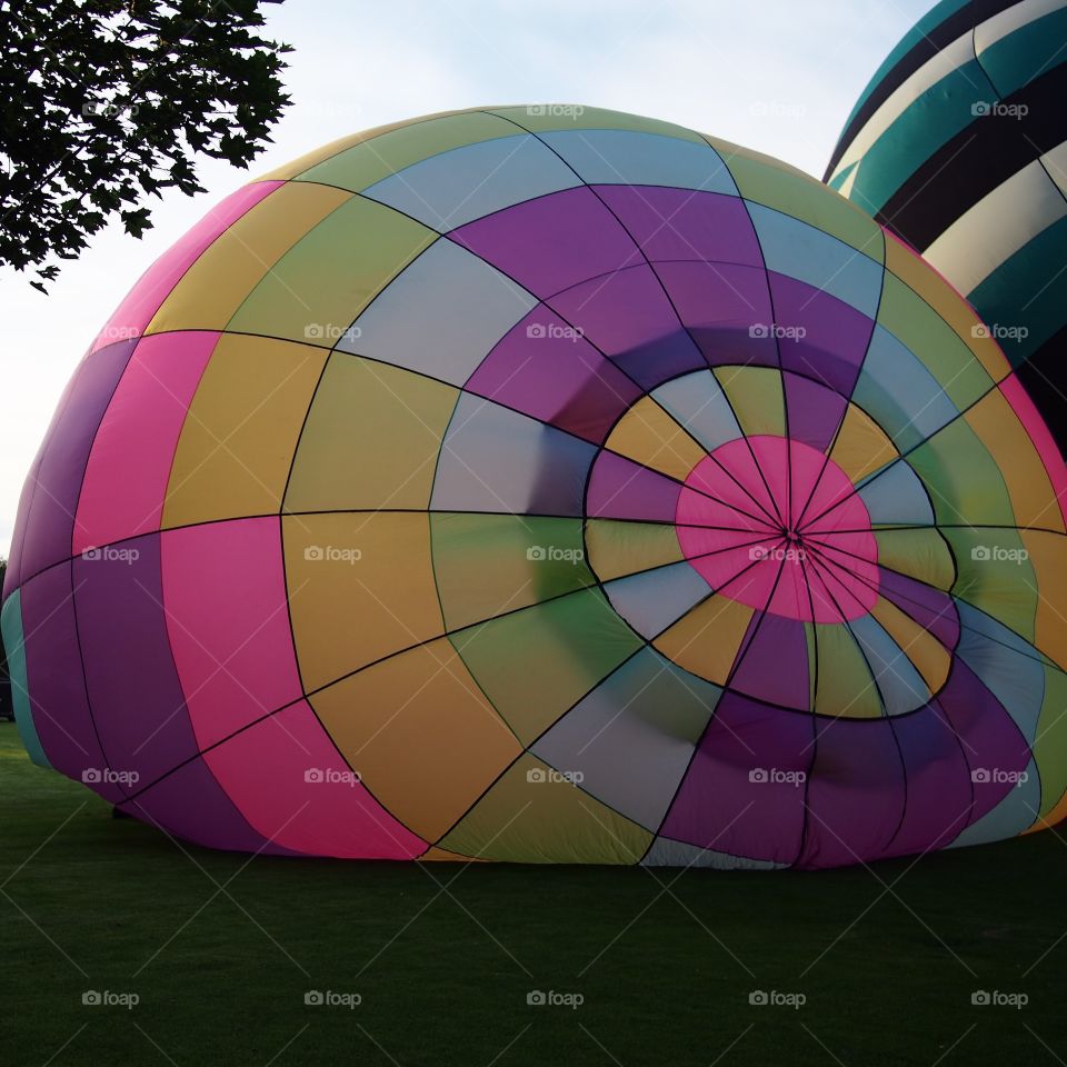 Two bright and colorful hot air balloons on the grass of Ochoco Park filling with helium for a morning flight over Prineville in Central Oregon on a beautiful summer morning as the sun rises.