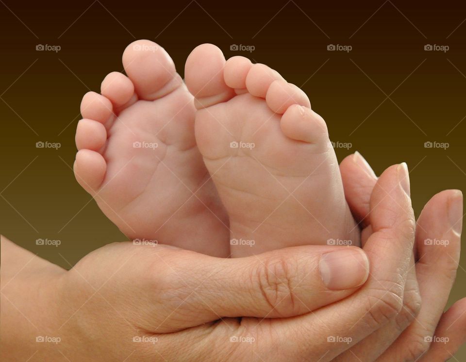 New mother holding infant’s feet 