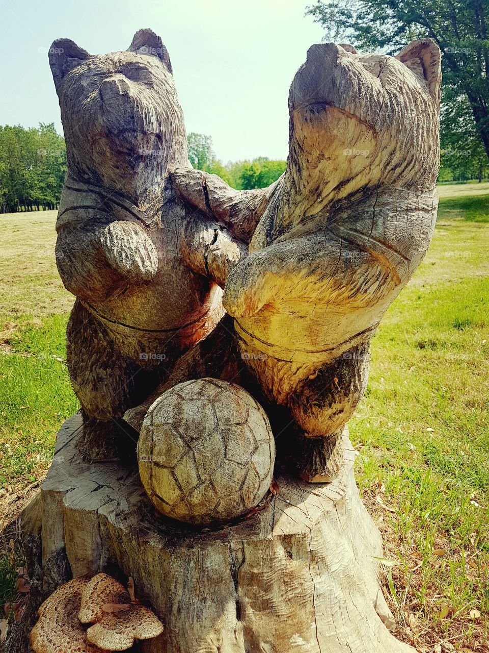 A wood carving of two bears playing soccer.