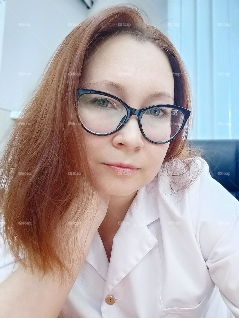 Medical girl with red hair, in a white coat, at work, with red hair. woman, selfie