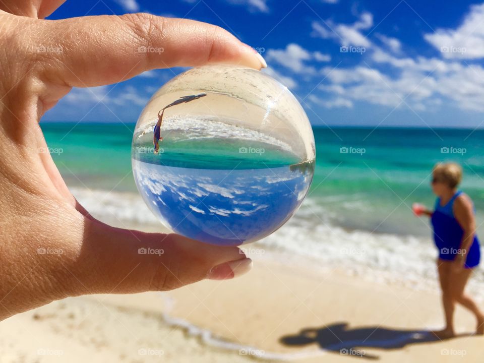 An abstract of the beach and a person walking as seen through a crystal lens ball 