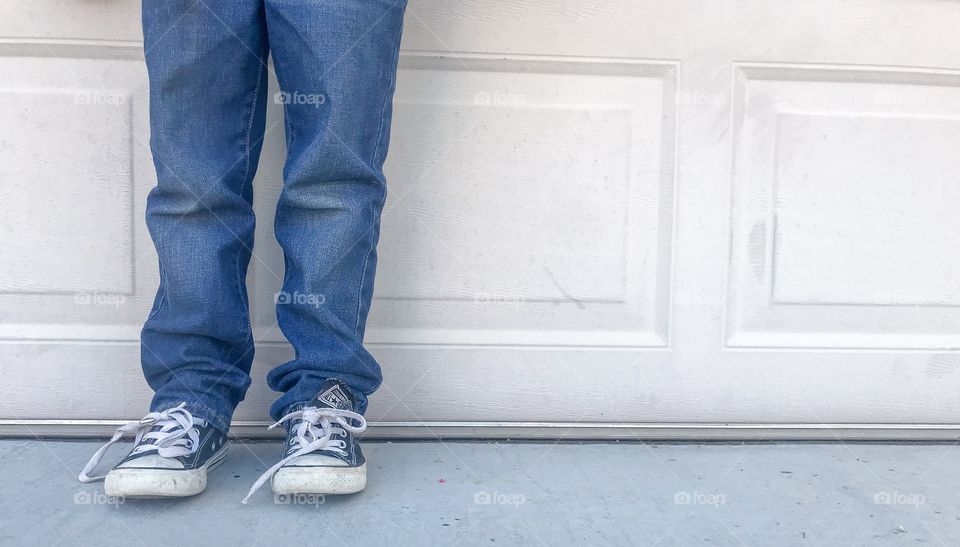 Boy in blue jeans and converse shoes standing 