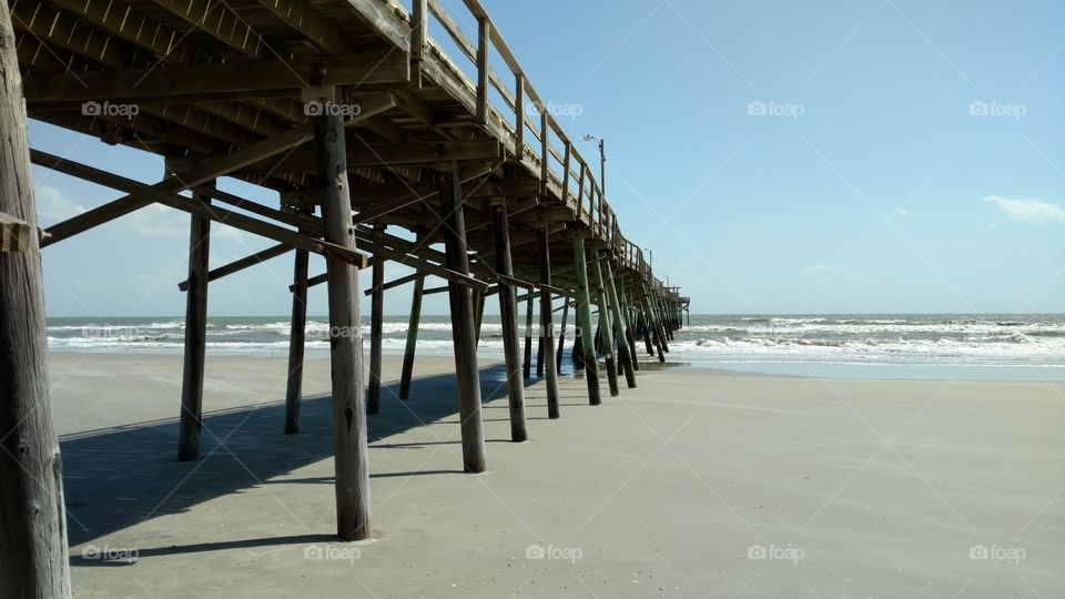Wooden pier on a sandy beach with the ocean in the background