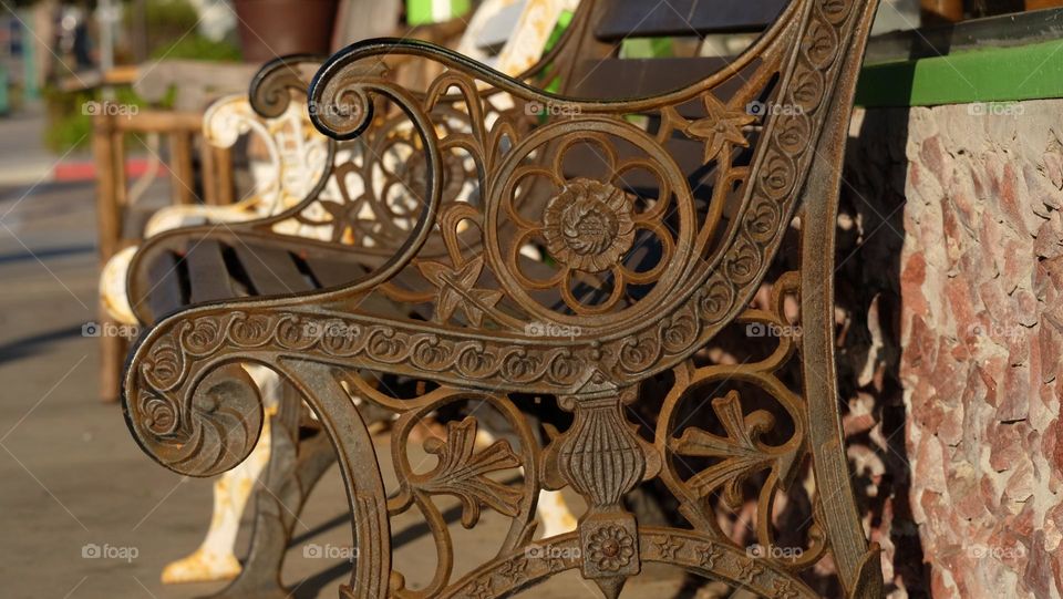 Antique style heavy iron bench adorned with beautiful curves and floral motifs.