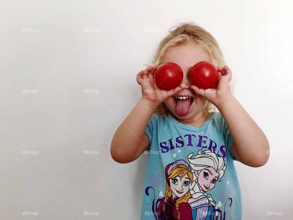 Girl holding tomatoes in front of her eyes