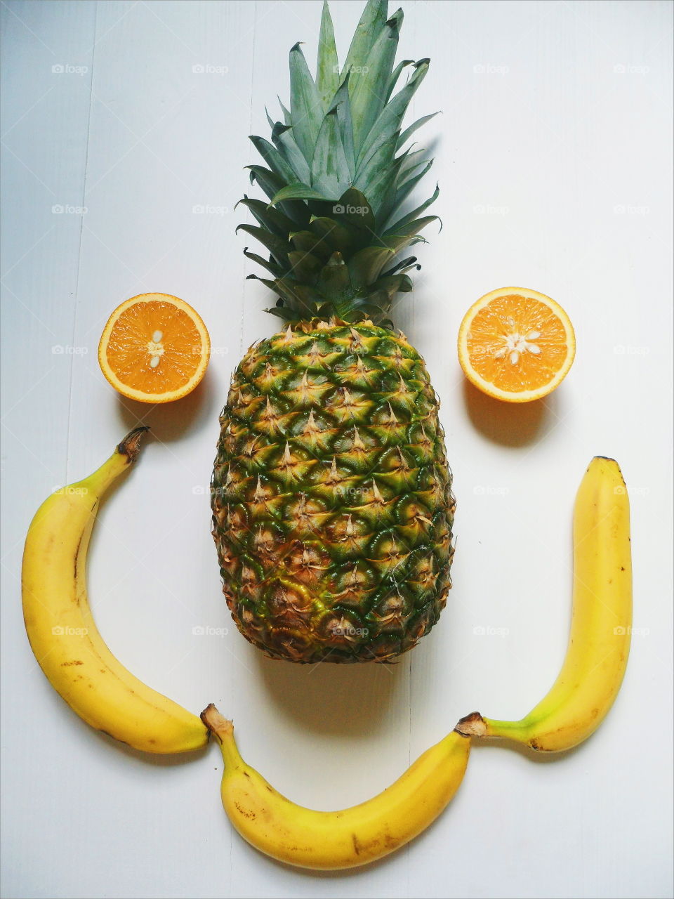 pineapple, sliced ​​orange and bananas on a white background
