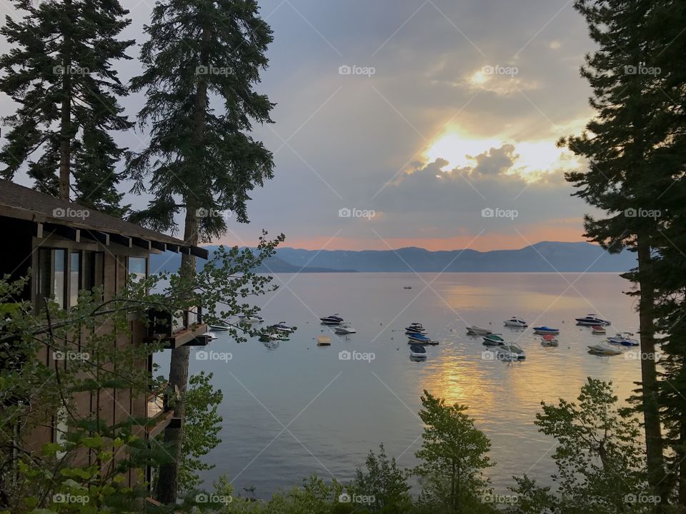 Lake Tahoe, California. Cabins next to water, boats on a lake, and mountains during sunrise.