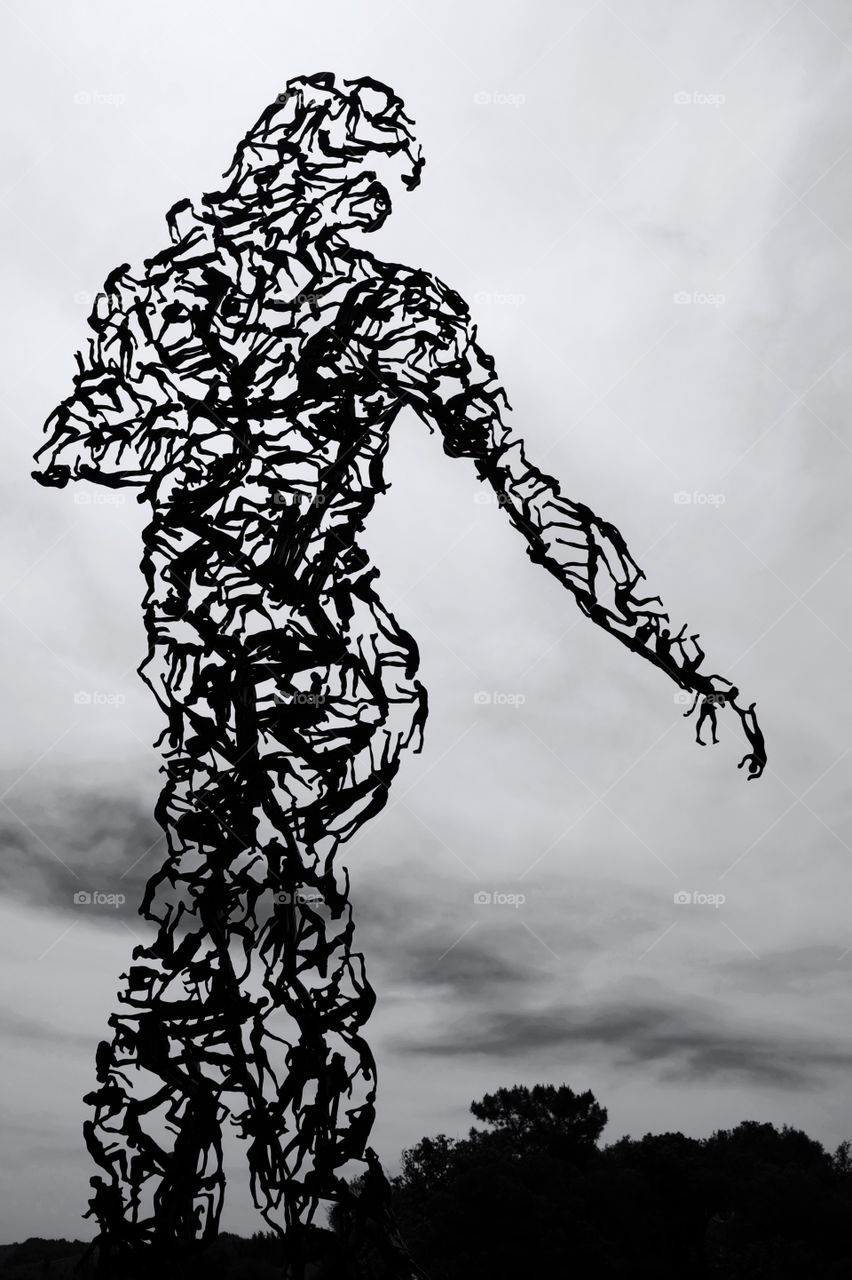 Silhouette of woman made up of many figures against sky