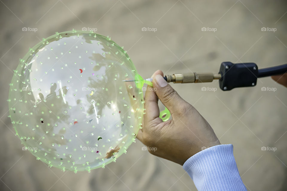 Hand holding a balloon and inflate with a needle.