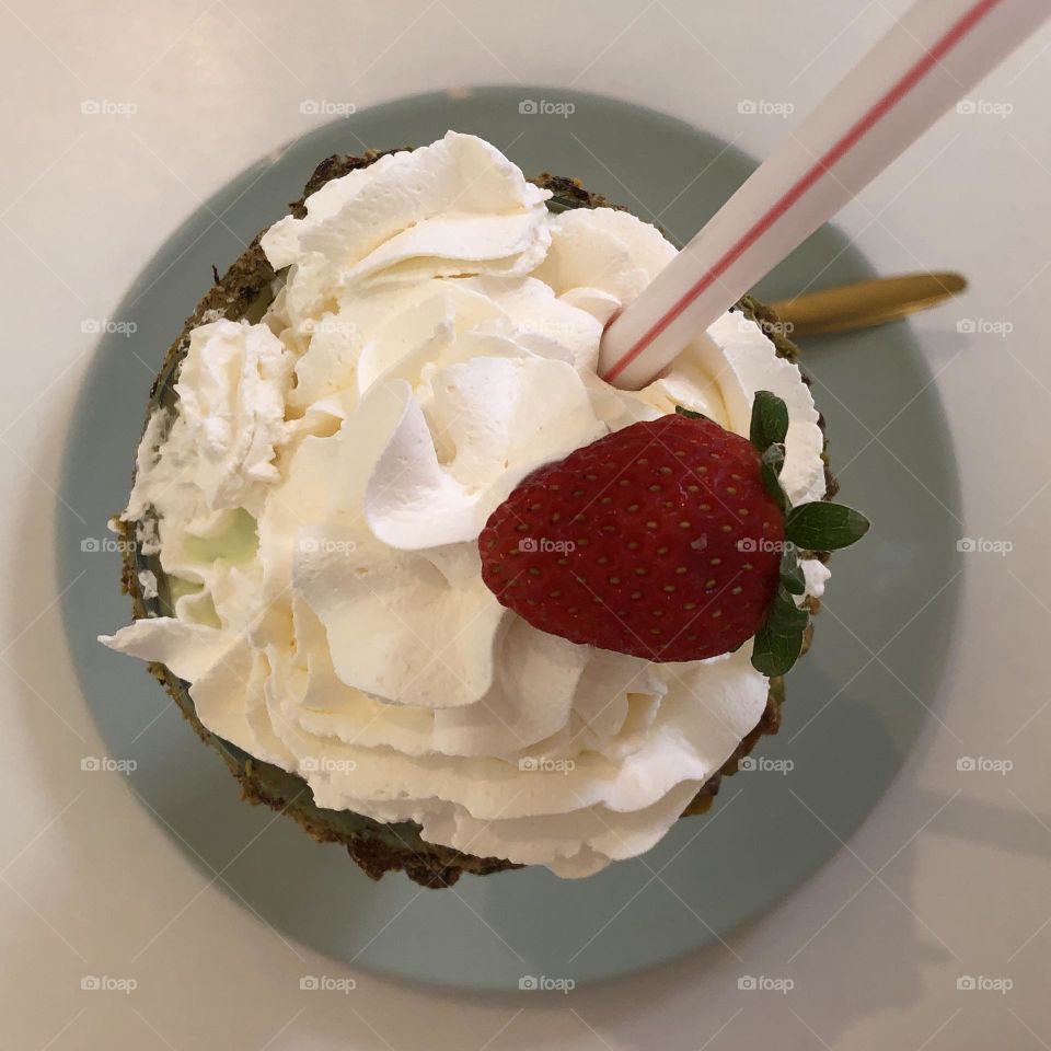 A delicious milkshake with whipped cream and a strawberry 