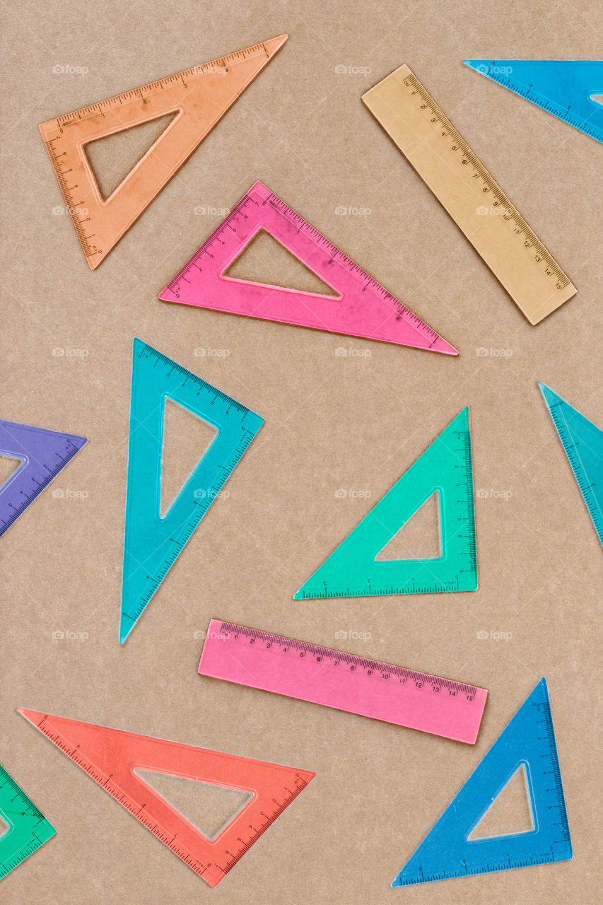 Overhead shot of arranged colorful set squares on brown paper