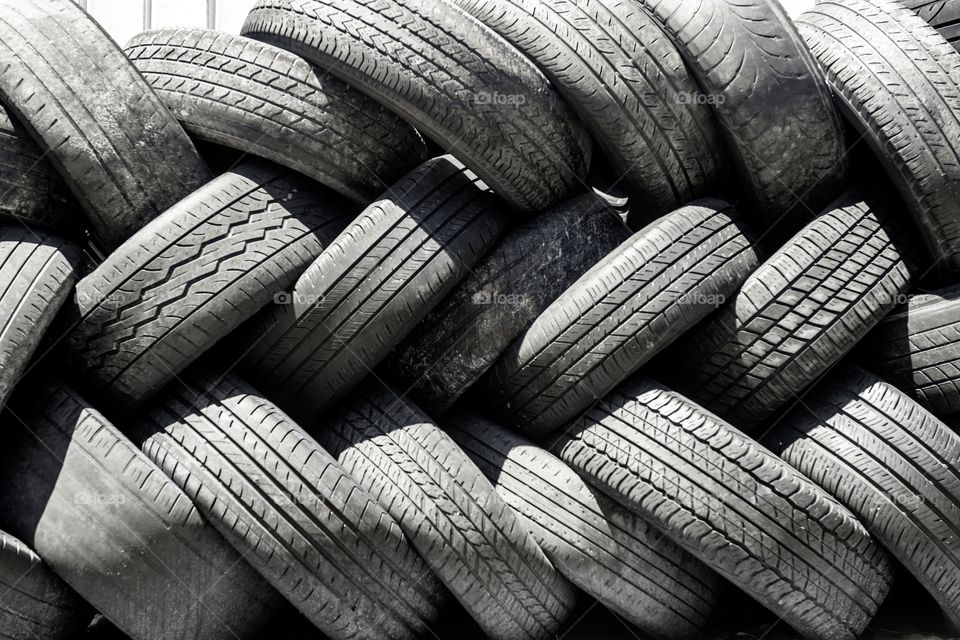 Background photo of used tires stacked on top of one another in closeup.