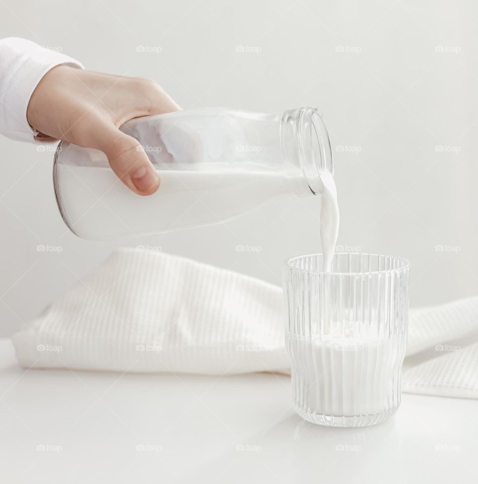 person pouring milk in the glass
