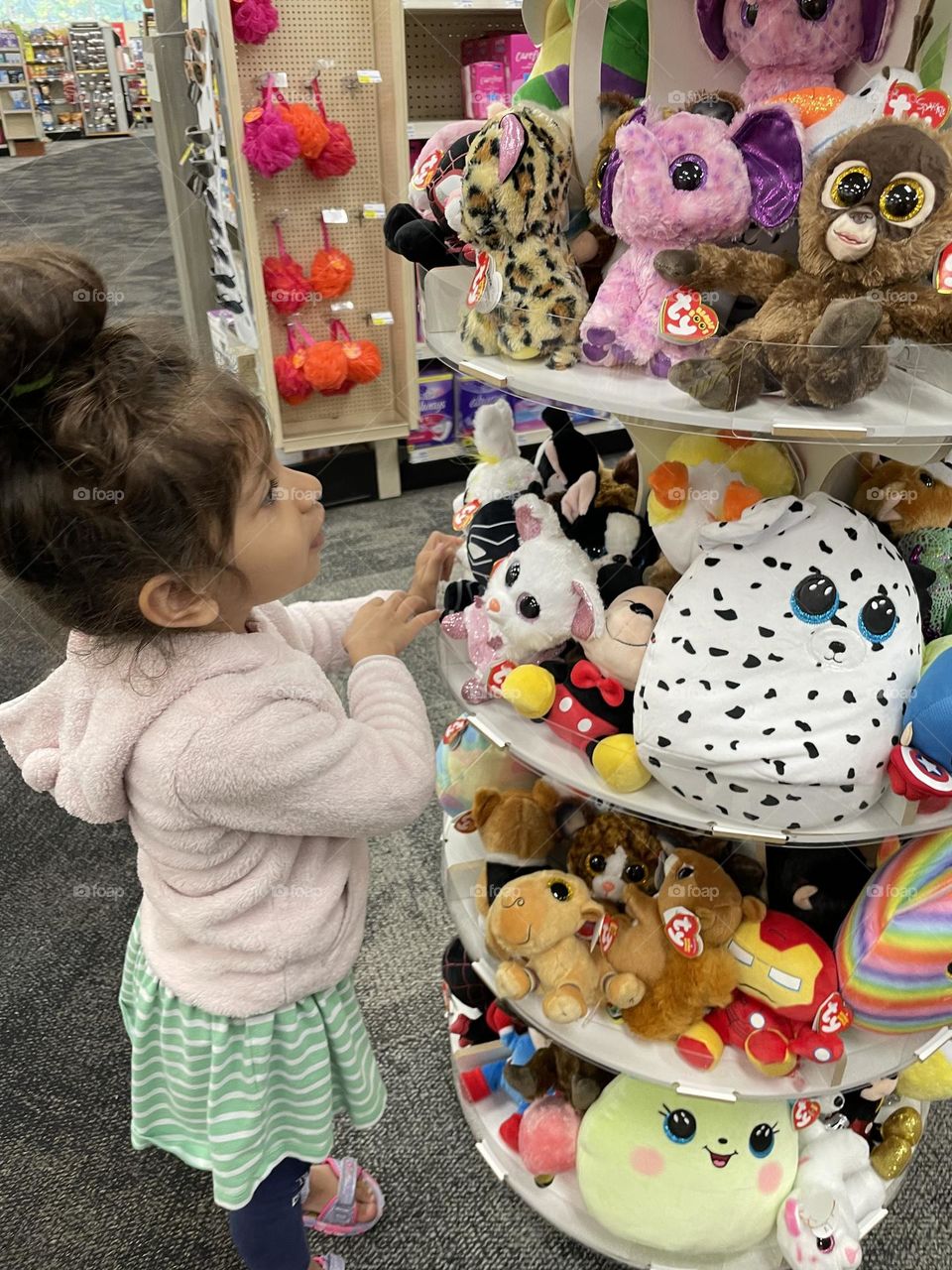 Little girl shops in CVS for stuffed animals, toddler girl wants to buy more stuffed animals, shopping for toys, buying toys with mommy, getting what you want 