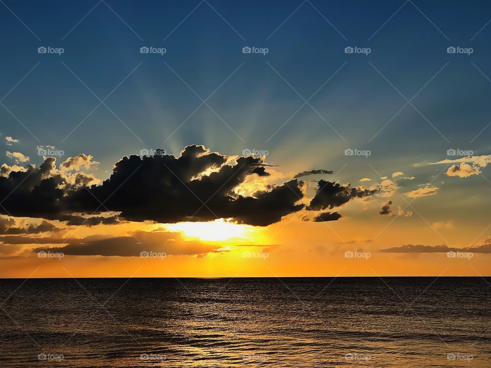 Beautiful celestial sunset bursting with lightrays over the ocean.